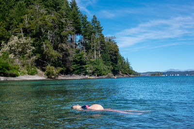 Man swimming in sea against sky