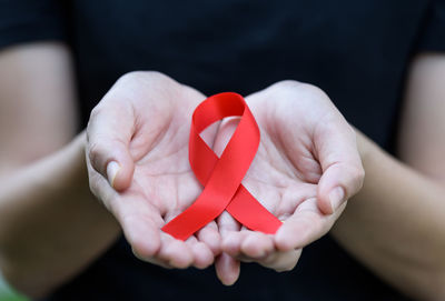 Midsection of woman with aids awareness ribbon on hand