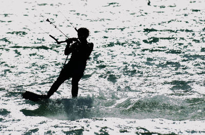 Silhouette man jumping on sea shore
