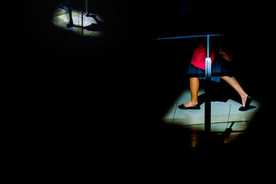 Low section of woman standing in dark room