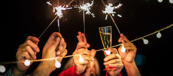 Caucasian adults dancing with sparklers and glasses with champagne
