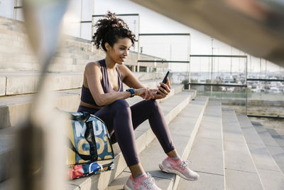 Female athlete using mobile phone while sitting on staircase