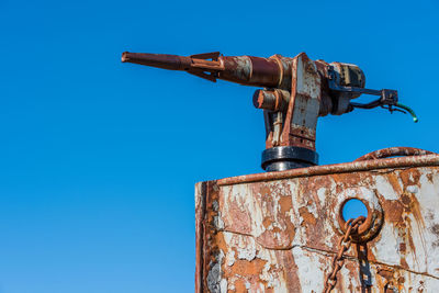 Low angle view of rusty metal against clear blue sky