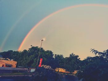 Low angle view of rainbow over building against sky