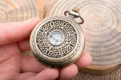 Close-up of hand holding pocket watch at table