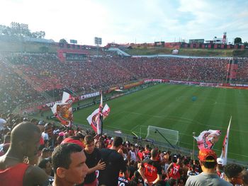 Crowd playing soccer on field against sky