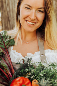 Close up portrait of a young female farmer smiling at camera holding