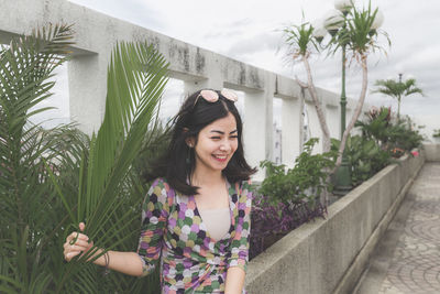 Portrait of smiling young woman standing against plants