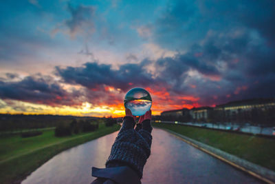 Man standing on road against sky at sunset