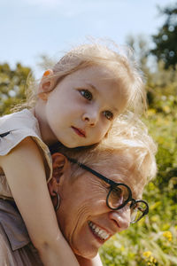 Happy senior woman piggybacking granddaughter at park