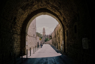 Narrow walkway leading towards cathedral against sky