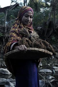 Full length of teenage girl holding tree in forest