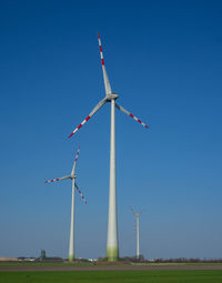 Low angle view of windmill on field against clear blue sky