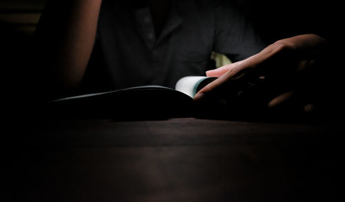 Midsection of person holding book on table at home