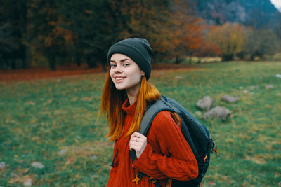 Young woman looking away while standing on field