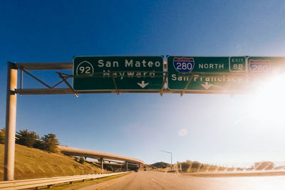 Information signs over road against clear blue sky