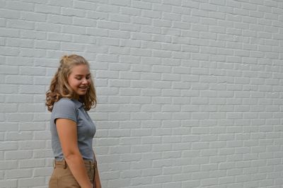 Portrait of smiling girl standing against brick wall