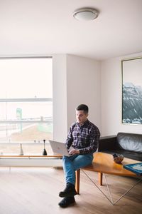 Full length of man using laptop while sitting at home