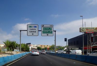 Information sign on road against sky in city
