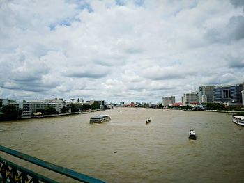 Boats in sea by cityscape against sky