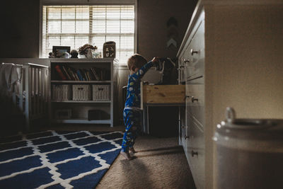 Side view of baby boy looking clothing in drawer at home