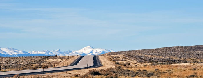 Scenic view of road by mountains against sky