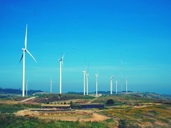 Windmills on farm against clear blue sky