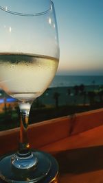 Close-up of beer in sea against sunset sky