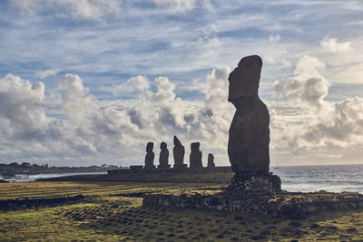 Panoramic view of moai statues on field against sky