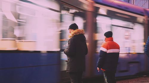 Rear view of people standing at railroad station