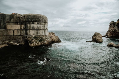 Scenic view of sea by buildings against sky