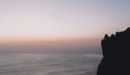 Silhouette man on beach against clear sky during sunset