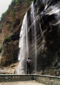 Man standing against waterfall