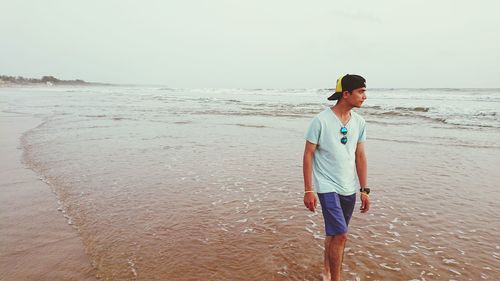 Man walking at beach against clear sky