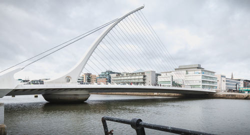 Bridge over river in city against sky