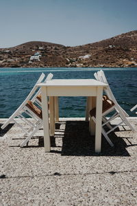 Chair on beach against clear sky