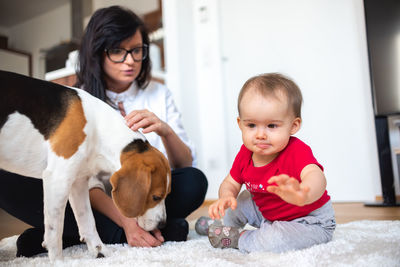 Baby with mother and beagle dog on carpet on the floor. baby activity theme