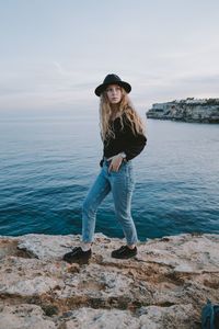 Portrait of smiling young woman standing in water against sky