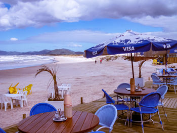 Chairs and tables on beach against sky