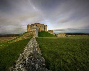 Old ruin building on field against cloudy sky