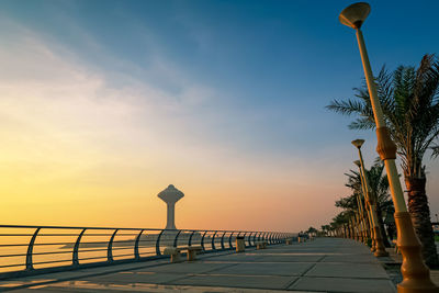 Street lights by road against sky during sunset