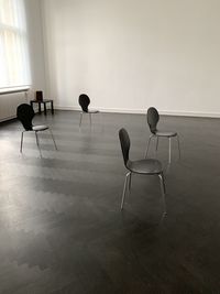 Empty chairs and table on hardwood floor against wall