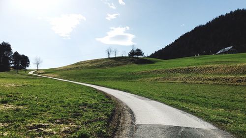 Road amidst field against sky