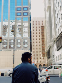 Rear view of man standing on street against buildings