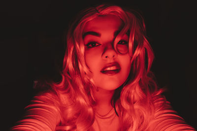 Portrait of beautiful young woman against black background