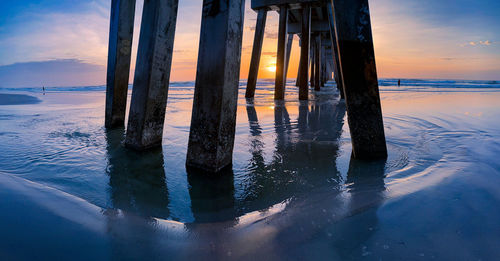 Pier over sea against sky during sunset