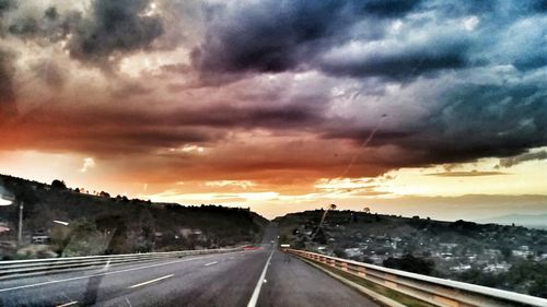 View of road against cloudy sky at sunset
