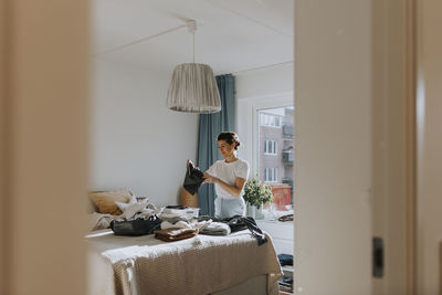 Woman folding clothes in bedroom