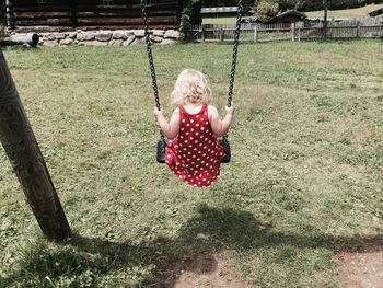 Rear view of girl on swing at field