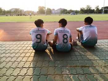 Rear view of players sitting on footpath at playground